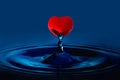 red heart is eating water drop splash in a glass cup blue colored.Valentines concept Royalty Free Stock Photo