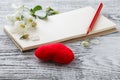 Red heart, flowering sprig, gift card on, around sprigs of flowering almonds on wooden background