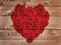 Red heart formed with roses on rustic wooden background