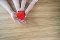 A red heart gift box in the hands of the child and mother on a white wooden background The concept of love Royalty Free Stock Photo