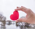 Red heart in the hand of the girl. river background