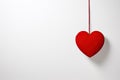 A red heart hanging from a string on a white wall Royalty Free Stock Photo