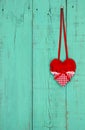 Red heart hanging on teal blue wood background