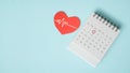 Red heart with heartbeat and calendar page with circle marked on 1st date on grunge blue background