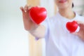 Red heart held by smiling female nurse`s hand, representing giving effort high quality service mind to patient. Professional, Spe