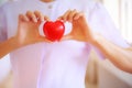 Red heart held by smiling female nurse`s hand, representing giving effort high quality service mind to patient. Professional, Spec