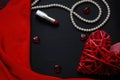Red heart and lipstick, on a black background, a string of white pearls and a silk handkerchief Royalty Free Stock Photo