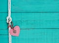 Red heart and lock hanging on rope knot against antique teal blue wooden background Royalty Free Stock Photo