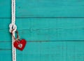 Red heart and lock hanging from rope knot border by antique blue wooden background Royalty Free Stock Photo