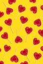 Red heart lollipops pattern on yellow background