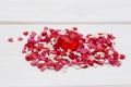 Red heart and many smaller hearts on a white wooden background.