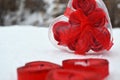 Red heart in the melted snow. three red candles in the shape of a heart.