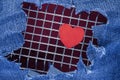 Red heart on a metal grill against the background of torn jeans. Background for Valentine`s Day Royalty Free Stock Photo