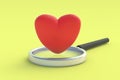 Red heart near magnifier on yellow background