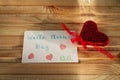A red heart with a note about the world kindness day lies on the wooden table