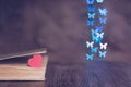 Red heart with an old book on the table and a background bokeh made of butterflies. Valentine`s day. Royalty Free Stock Photo