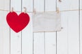 Red heart and old paper blank hanging at clothesline on wood white background with space. Valentine Day. Royalty Free Stock Photo