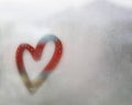 Red heart outline painted on sweaty glass, there are many drops on it, inscription heart and love handmade on wet autumn foggy