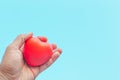 Red heart in the palm of a hand on a blue background