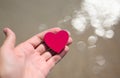 Red heart in the palm of your hand against the backdrop of the reflections of the sea. Royalty Free Stock Photo