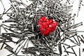 Red heart on pile of iron grey nails, pierced by a nails Royalty Free Stock Photo