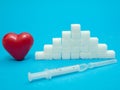 Red heart, pile of white sugar cubes, syringe with insulin