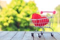 A red heart pillow in mini shopping cart on wooden table. Royalty Free Stock Photo