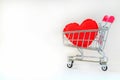 A red heart pillow in pink mini shopping cart on wooden table on Royalty Free Stock Photo