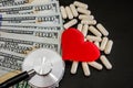 Red heart, pills, stethoscope, dollars on a black background. Health concept.