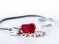 Red heart, pills and stethoscope on white background.