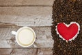 red heart on Roasted coffee beans and cup of milk coffee on wood table, love coffee concept Royalty Free Stock Photo