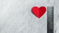 Red heart with ruler on white marble background. Royalty Free Stock Photo