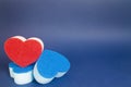Red heart shape dishwash sponge over two blue heart shape dishwasher sponge in the foreground on the blue background Royalty Free Stock Photo