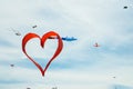 Red heart shape kite is flying in blue sky