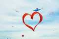 Red heart shape kite is flying in blue sky