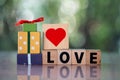 Red heart shape in wooden cube place on wooden cube text of love near gift box Royalty Free Stock Photo