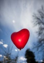 Red heart-shaped balloon in sky