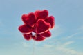 Red heart-shaped balloons with blue sky background in vintage style, concept of love in summer and valentine, wedding Royalty Free Stock Photo