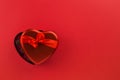 Red heart-shaped box with chocolate candy on red background Royalty Free Stock Photo