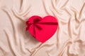 Red heart-shaped box wrapped ribbon now on silk background. Happy Valentines Day concept. Flat lay, top view Royalty Free Stock Photo