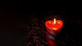 A red heart-shaped candle burns on a dark background. Copy space. Royalty Free Stock Photo