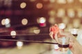 A red heart shaped candle in a woman`s hand with candlelight in many small glass cups.