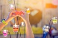 A red heart shaped candle in a woman`s hand with candlelight in many small glass cups.