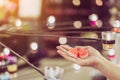 A red heart shaped candle in a woman`s hand with candlelight in many small glass cups.