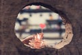 A red heart shaped candle in a woman`s hand with candlelight in many small glass cups.