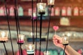 A red heart shaped candle in a woman`s hand with candlelight in many small glass cups.