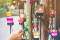 A red heart shaped candle in a woman`s hand with candlelight in many small glass cups.