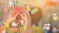 A red heart shaped candle in a woman`s hand with candlelight in many small glass cups.