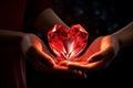 A red heart-shaped crystal in the hands of a couple in love. Luxurious red decoration for Valentines Day Royalty Free Stock Photo