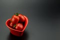 Red heart-shaped dish and small tomatoes Royalty Free Stock Photo